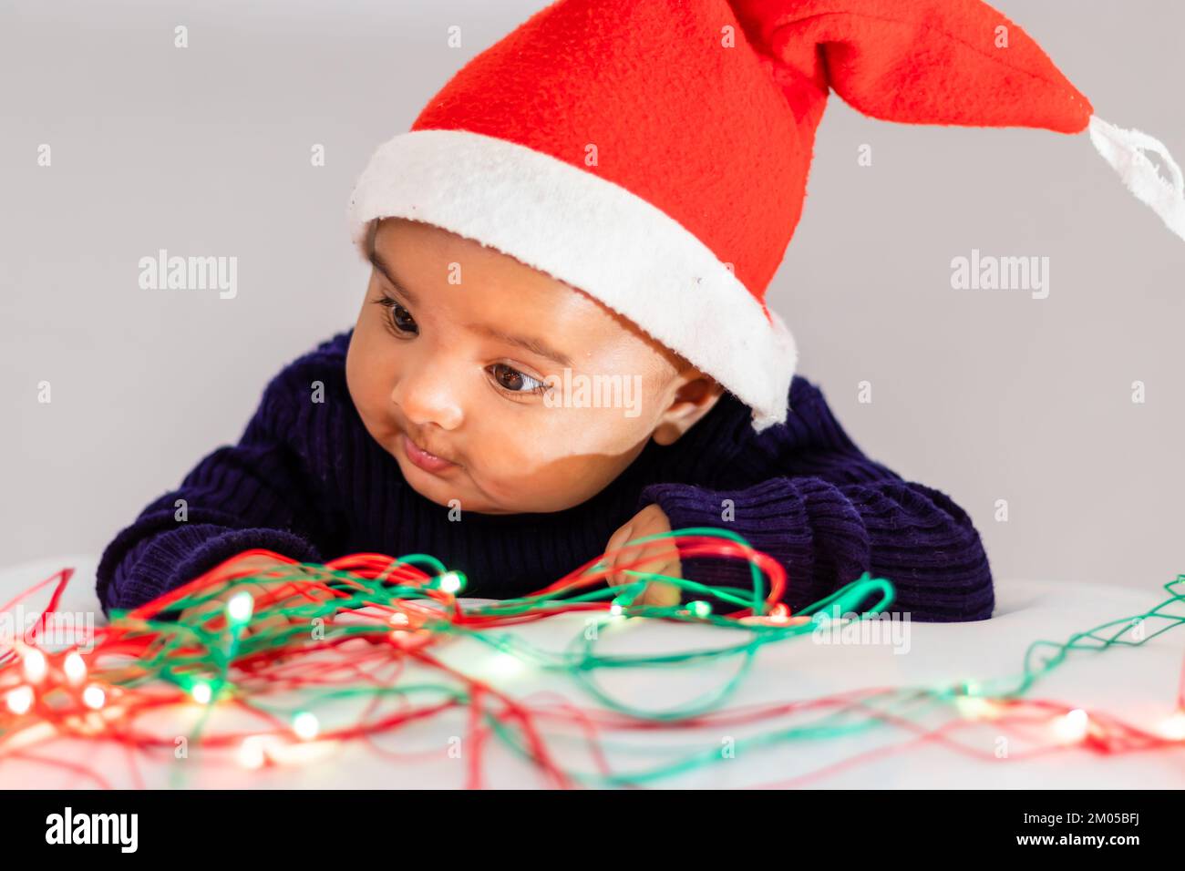infant boy wearing Christmas red cap playing cute facial expression with white background at indoor Stock Photo