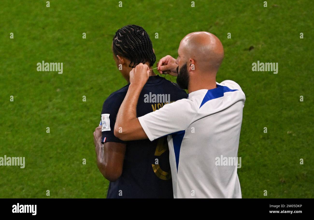 Doha, Qatar. 4th Dec, 2022. Jules Kounde (L) of France has his necklace taken off during the Round of 16 match between France and Poland of the 2022 FIFA World Cup at Al Thumama Stadium in Doha, Qatar, Dec. 4, 2022. Credit: Xia Yifang/Xinhua/Alamy Live News Stock Photo