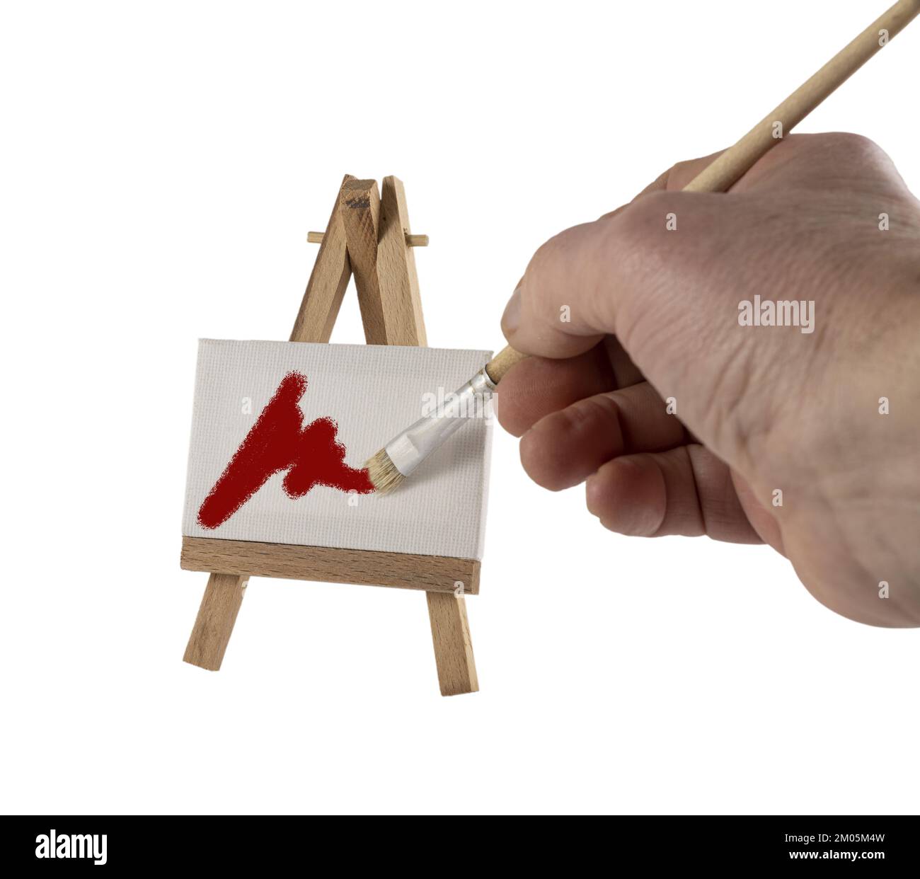 a male hand paints a canvas on the miniature easel Stock Photo