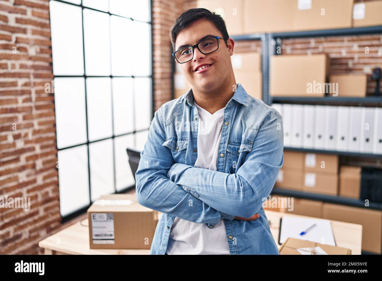 Down syndrome man ecommerce business worker standing with arms crossed gesture at office Stock Photo