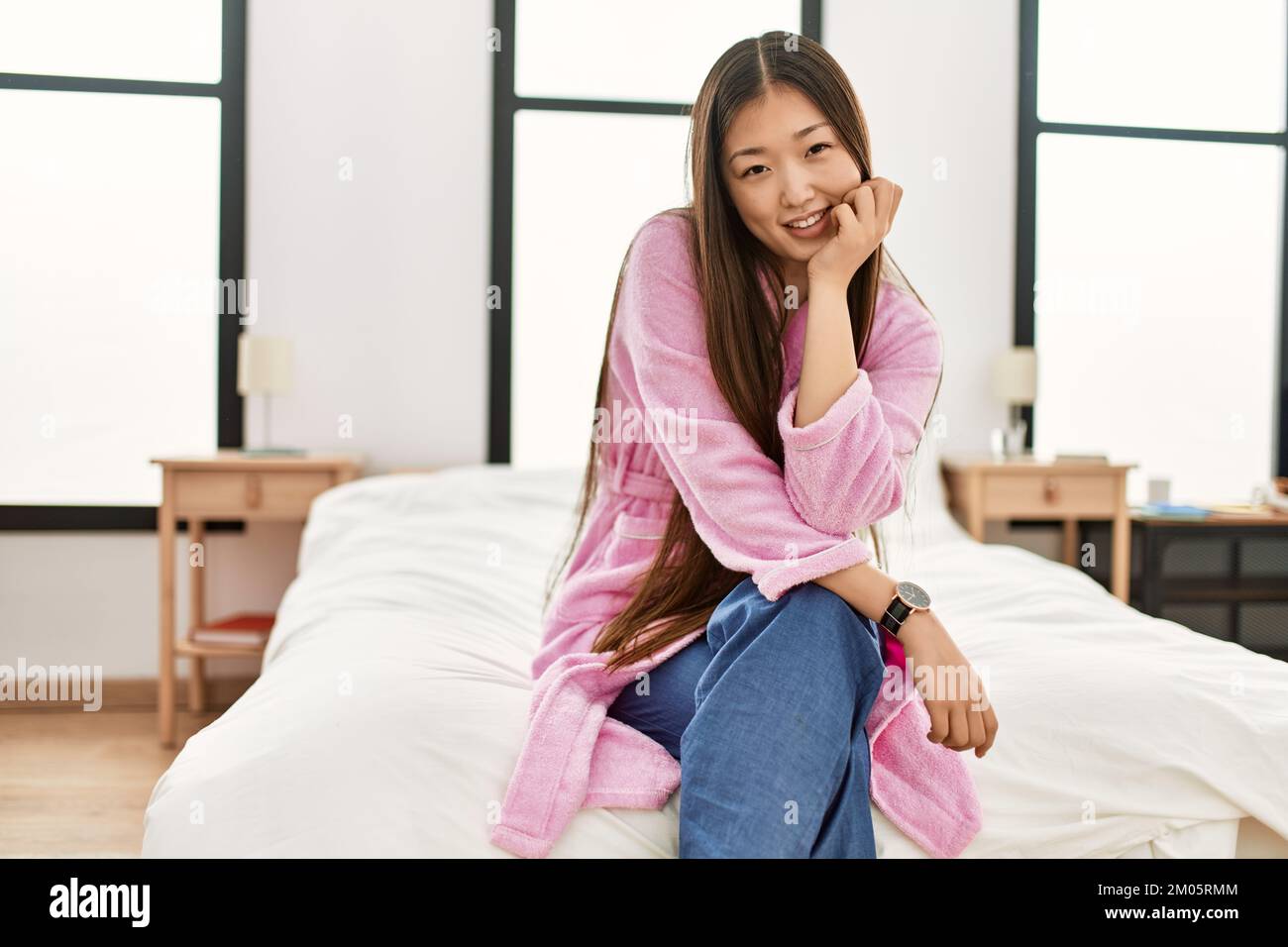 Young chinese girl smiling happy sitting on the bed at bedroom Stock ...