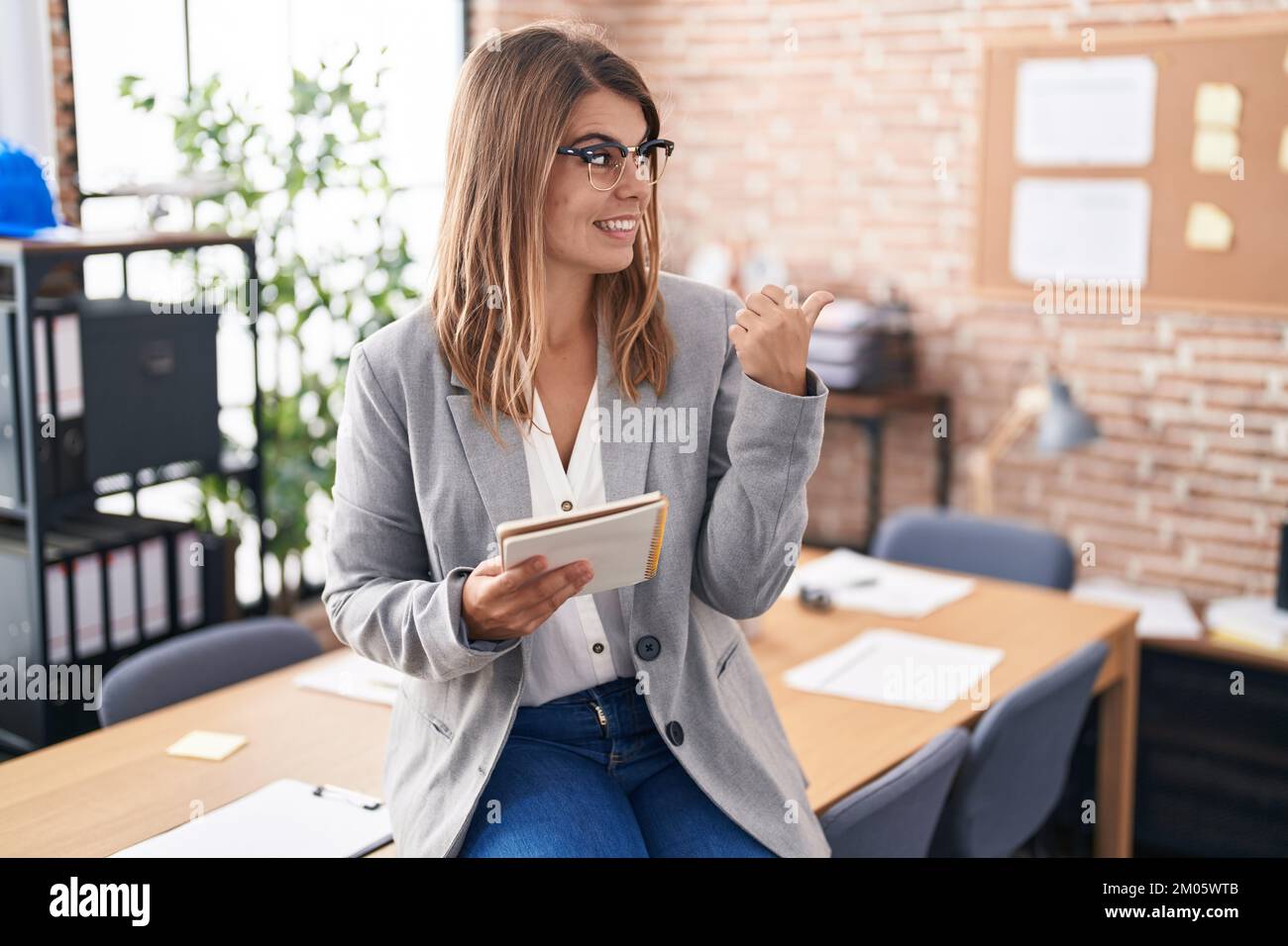 Young hispanic woman working at the office wearing glasses smiling with ...