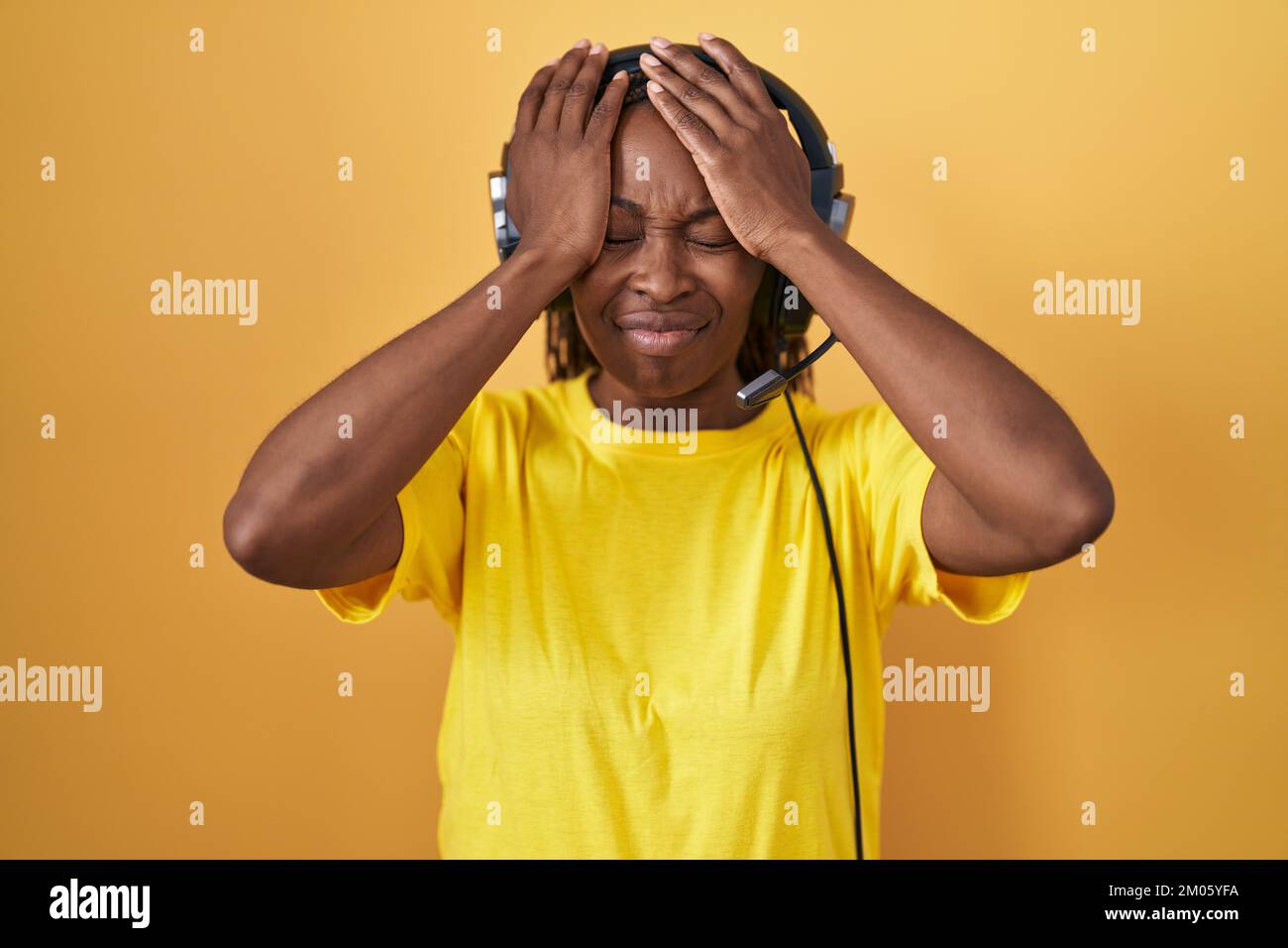 African american woman listening to music using headphones suffering