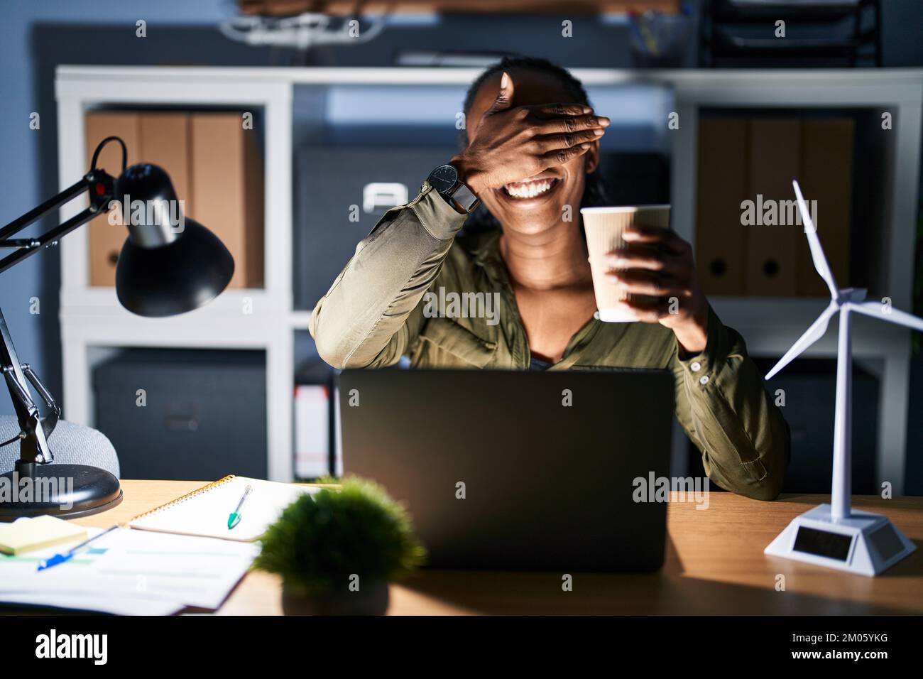 African woman working using computer laptop at night smiling and ...