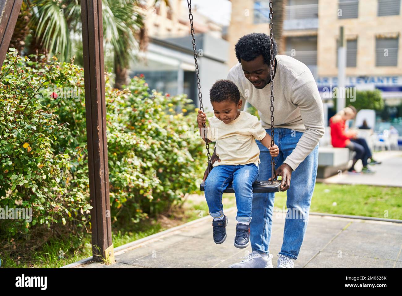 Father and son playing on swing at playground Stock Photo - Alamy