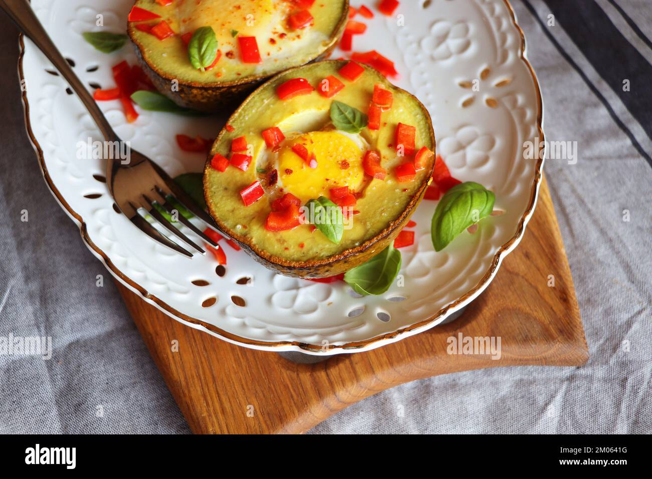 Keto diet. Healthy breakfast of baked avocado and eggs boats with herbs . Stock Photo