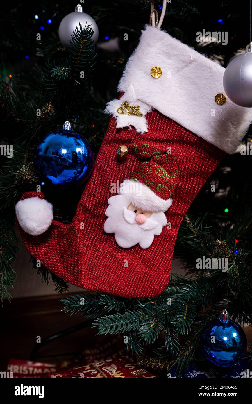 Christmas stocking. Red sock with snowflakes for Santa's gifts hanging on the Christmas tree. Winter holidays decoration Stock Photo