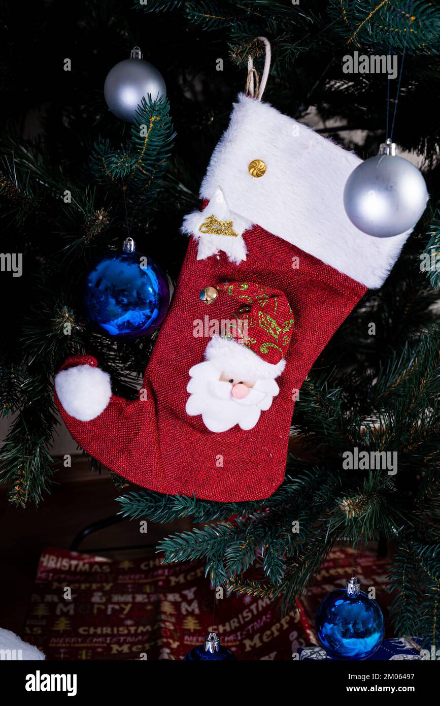 Christmas stocking. Red sock with snowflakes for Santa's gifts hanging on the Christmas tree. Winter holidays decoration Stock Photo