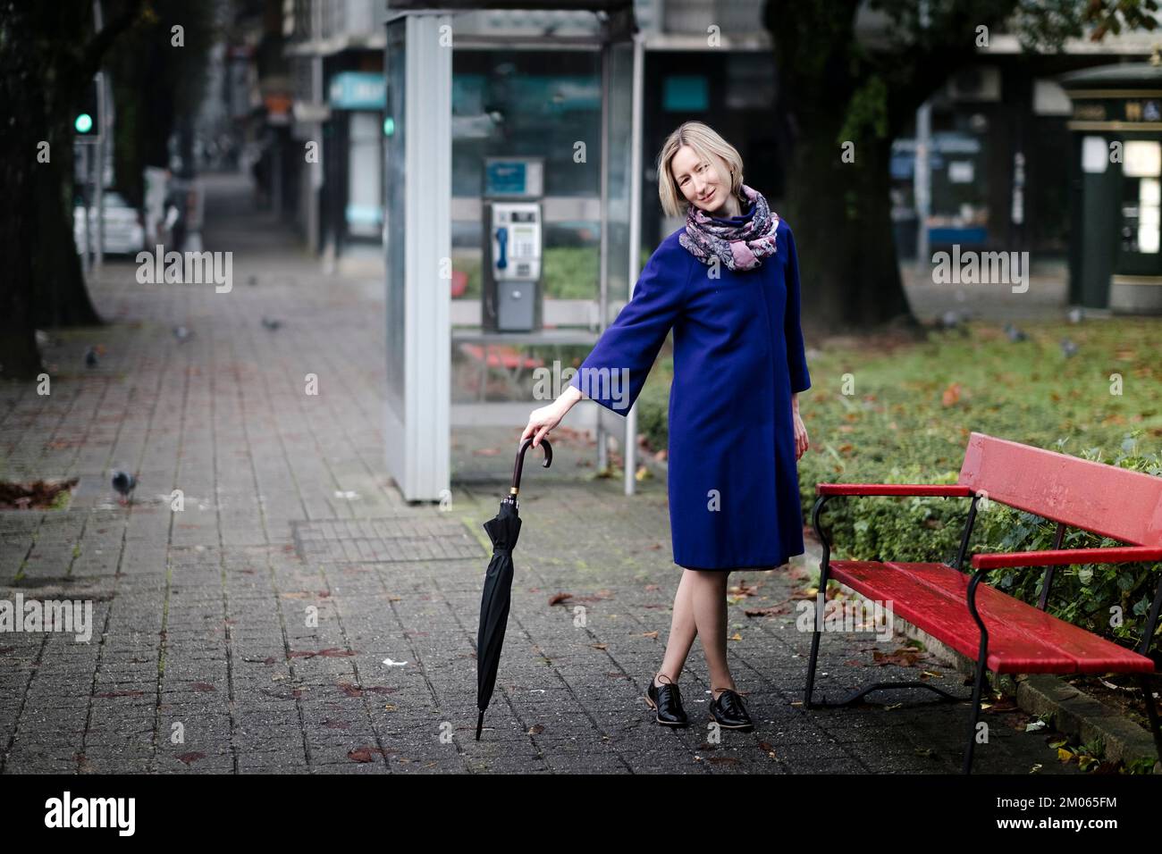 A woman with an umbrella is outside on the street. Stock Photo