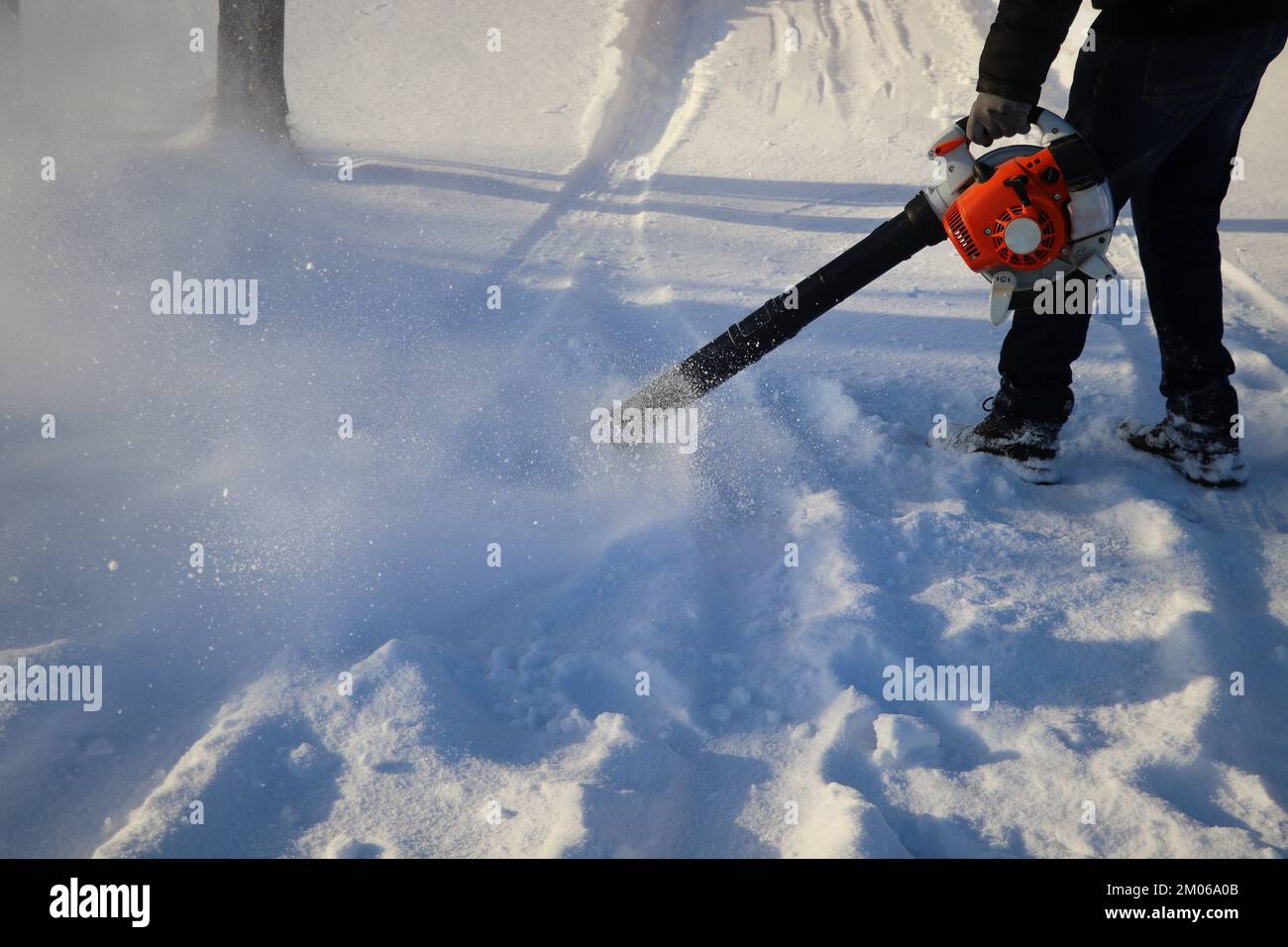 Worker cleaning pavement from snow with blower . Stock Photo