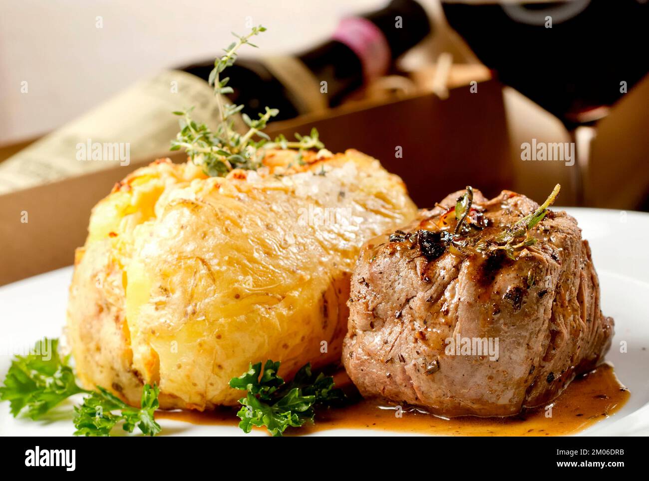 Filet mignon beef steak with gravy and stuffed potato served on a plate paired with red wine glass and bottle. Premium quality restaurant Gourmet food Stock Photo