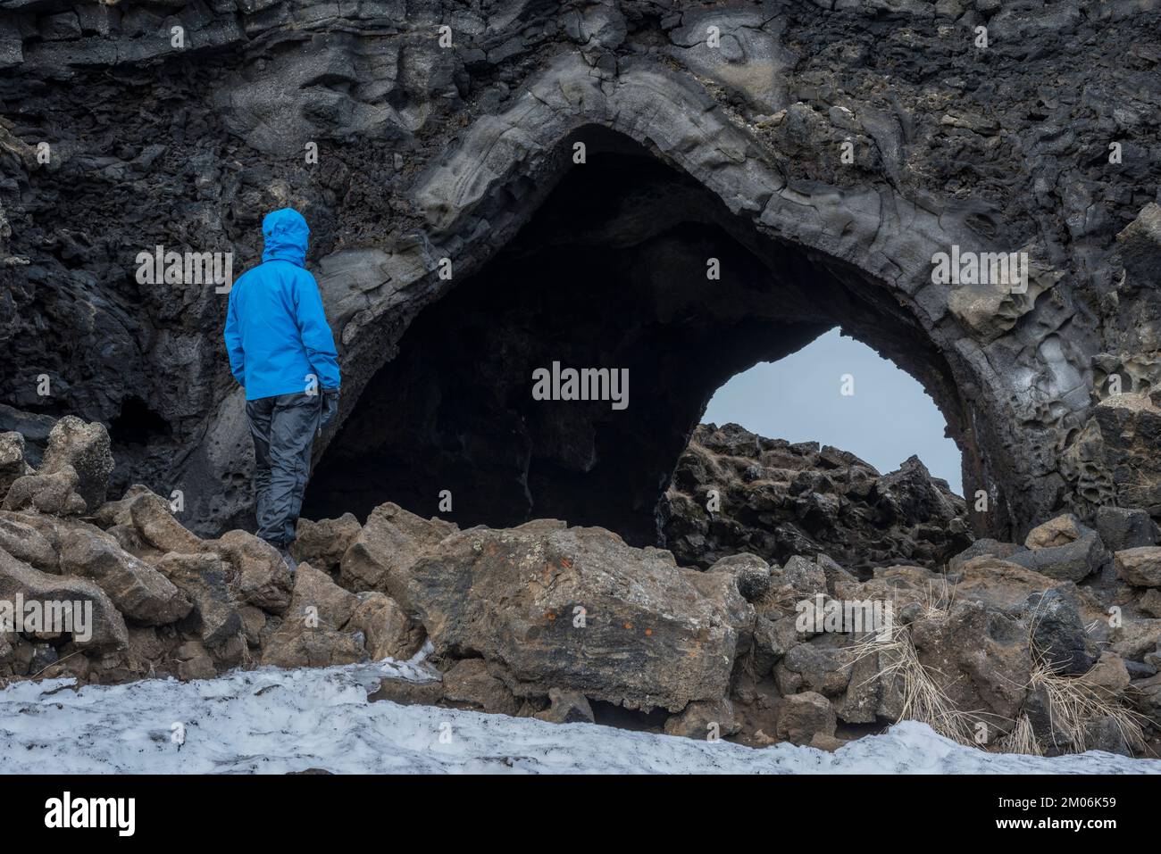 Tourist in front of a tunnel in lava field, winter, Dimmuborgir, Mývatn region, Myvatn, Iceland Stock Photo