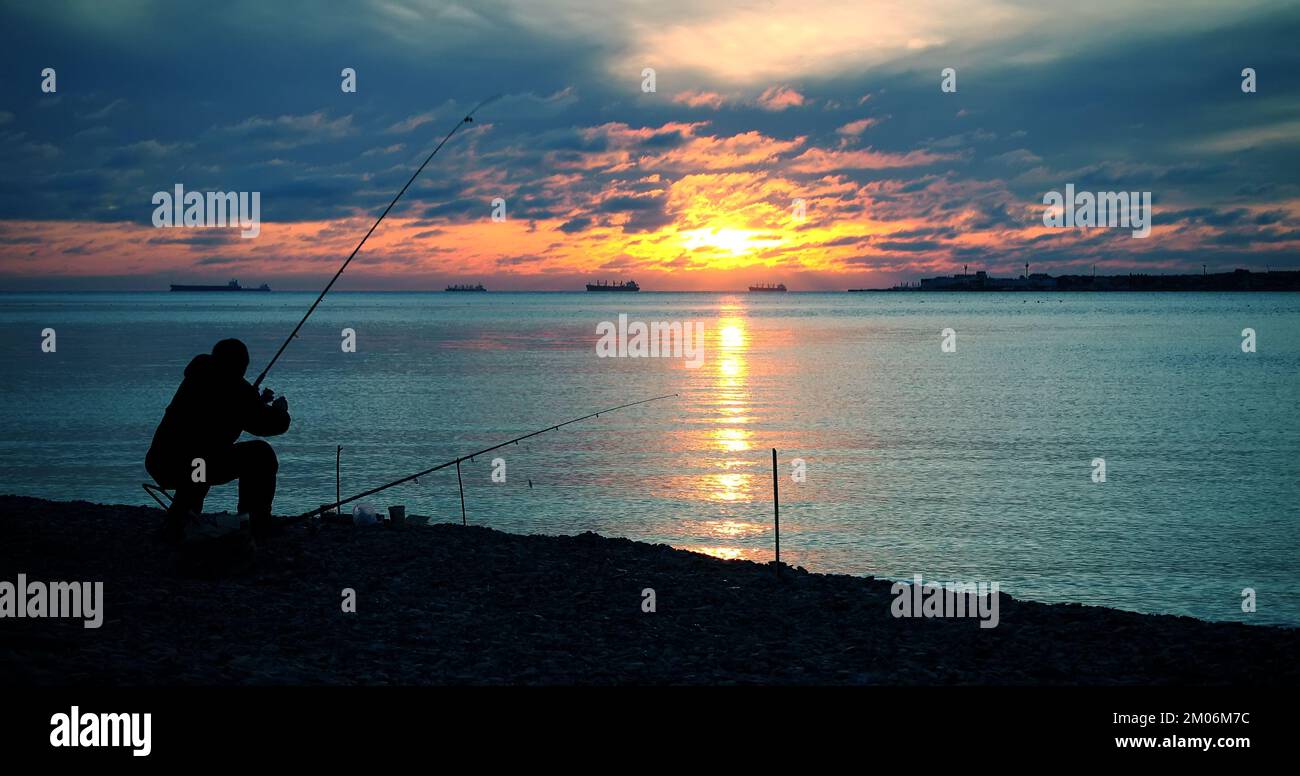 Fisherman catches fish, majestic sunset around Stock Photo