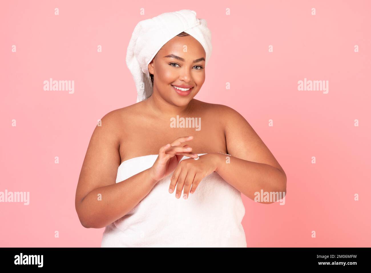Skin care cosmetics concept. Excited oversized black lady applying ...