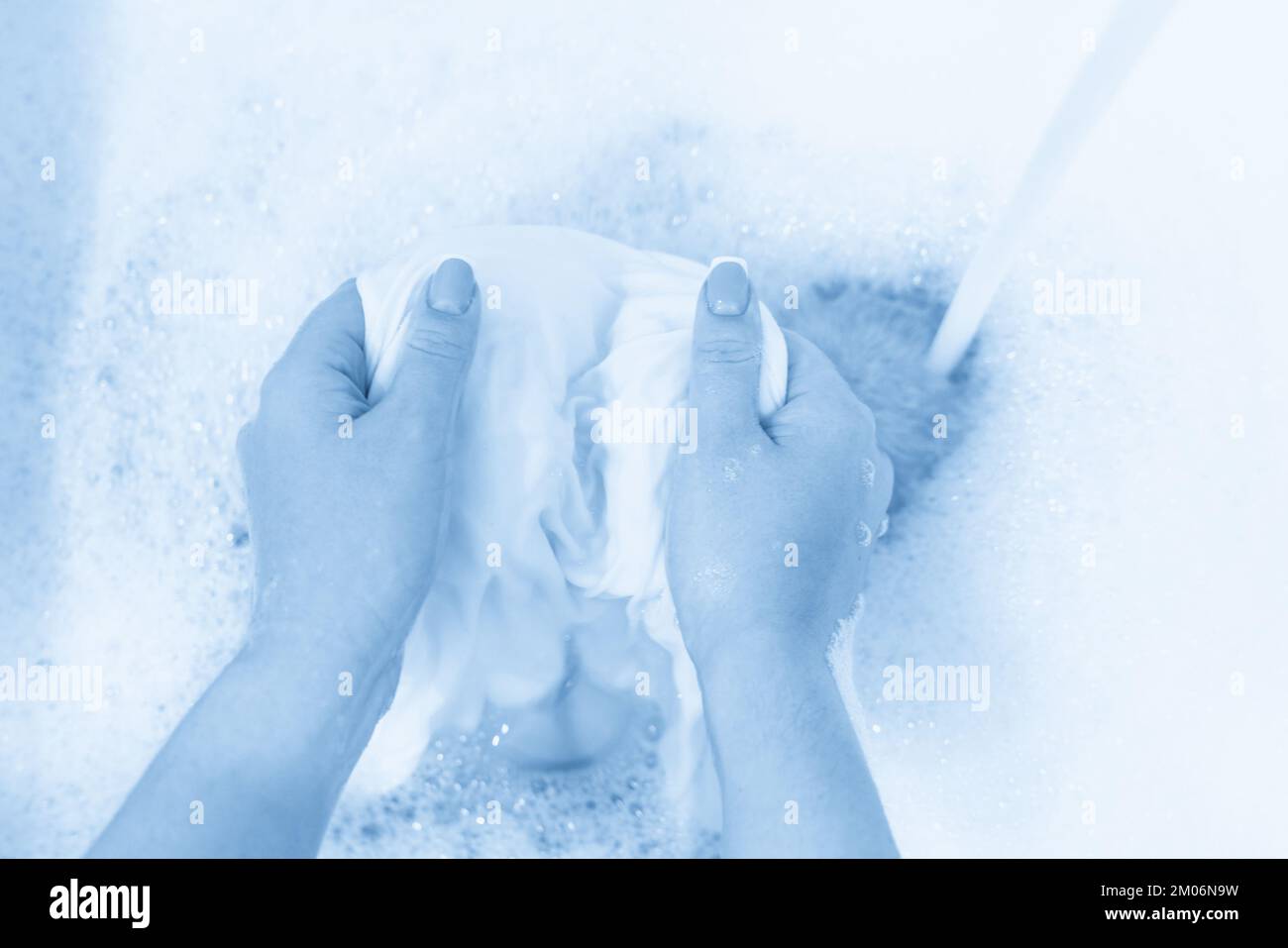 Wash clothing by hand with whitening detergent in laundry sink Stock