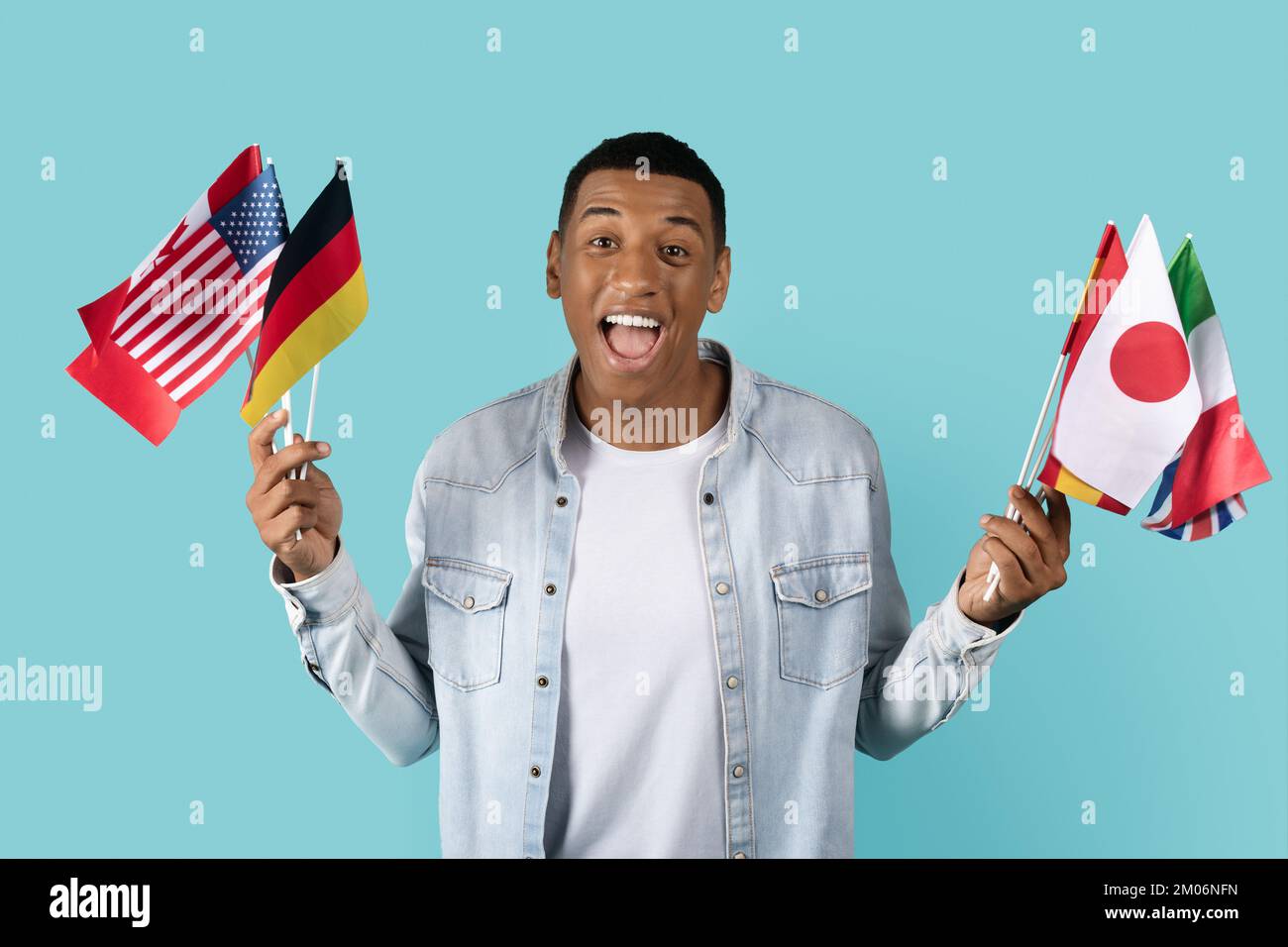 Glad young african american guy student in casual with open mouth shows many flags of different countries Stock Photo
