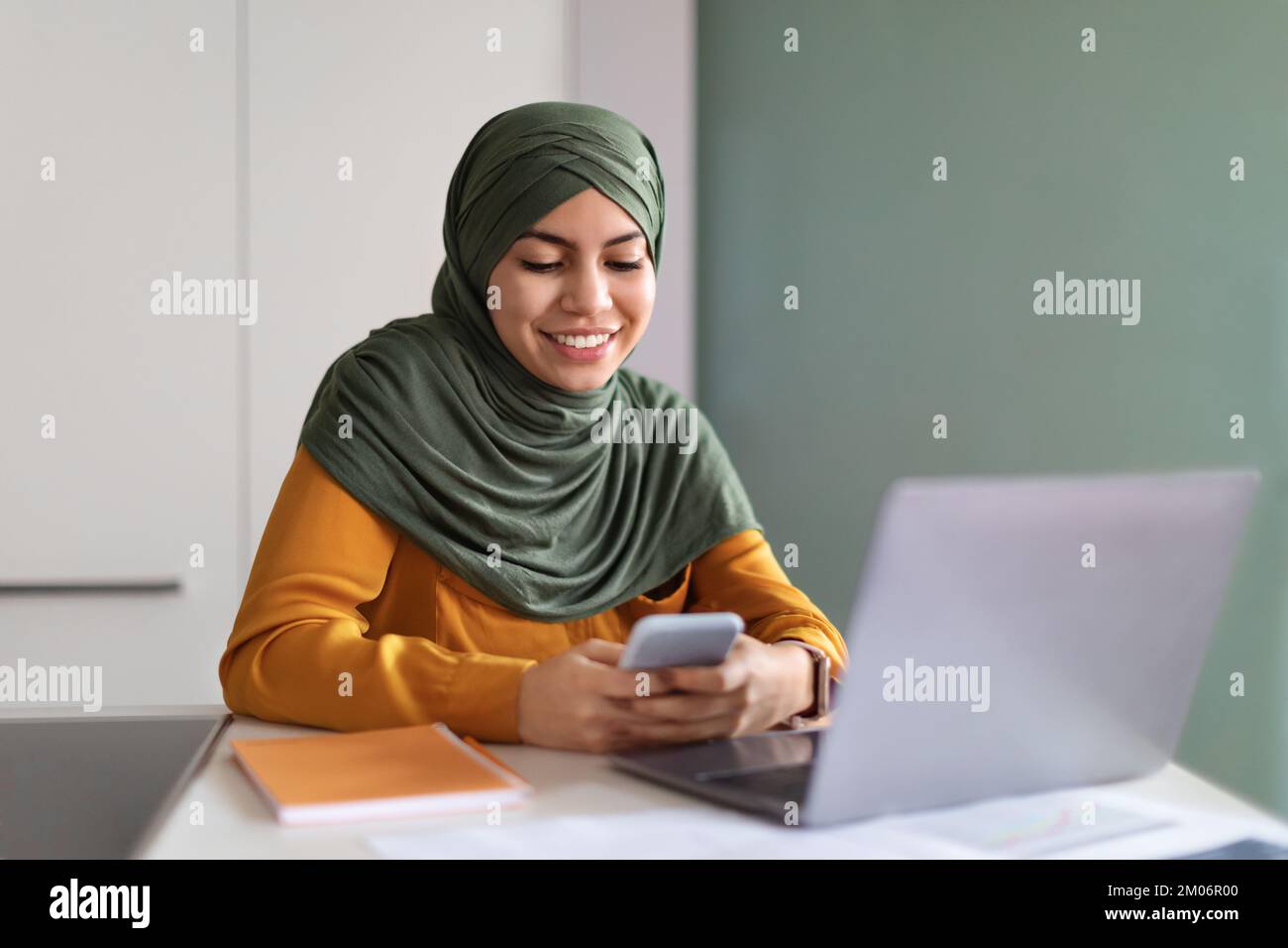 Smiling Young Muslim Woman In Hijab Using Smartphone In Office Stock ...