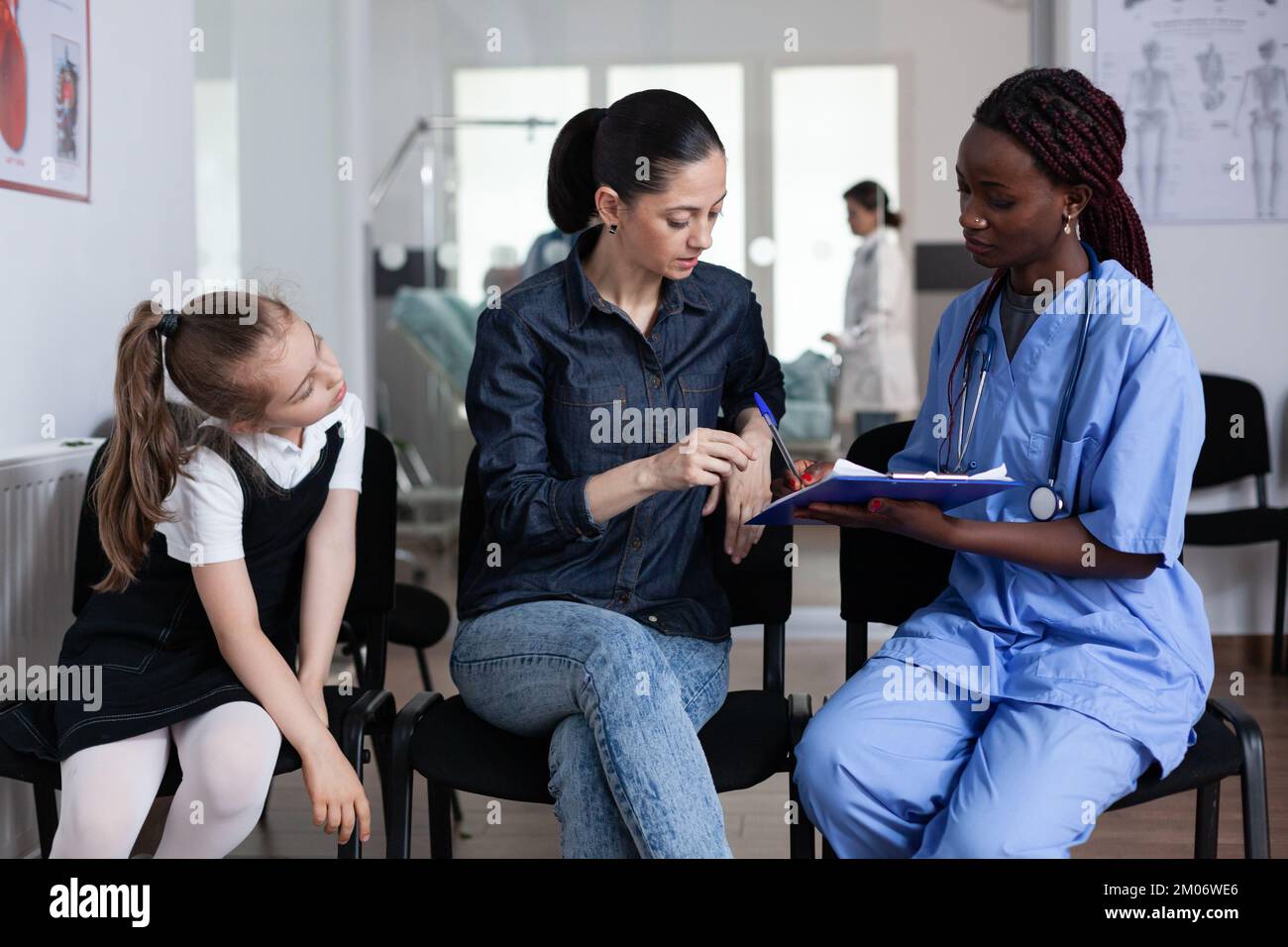 Young woman signing little girl discharge papers in children hospital