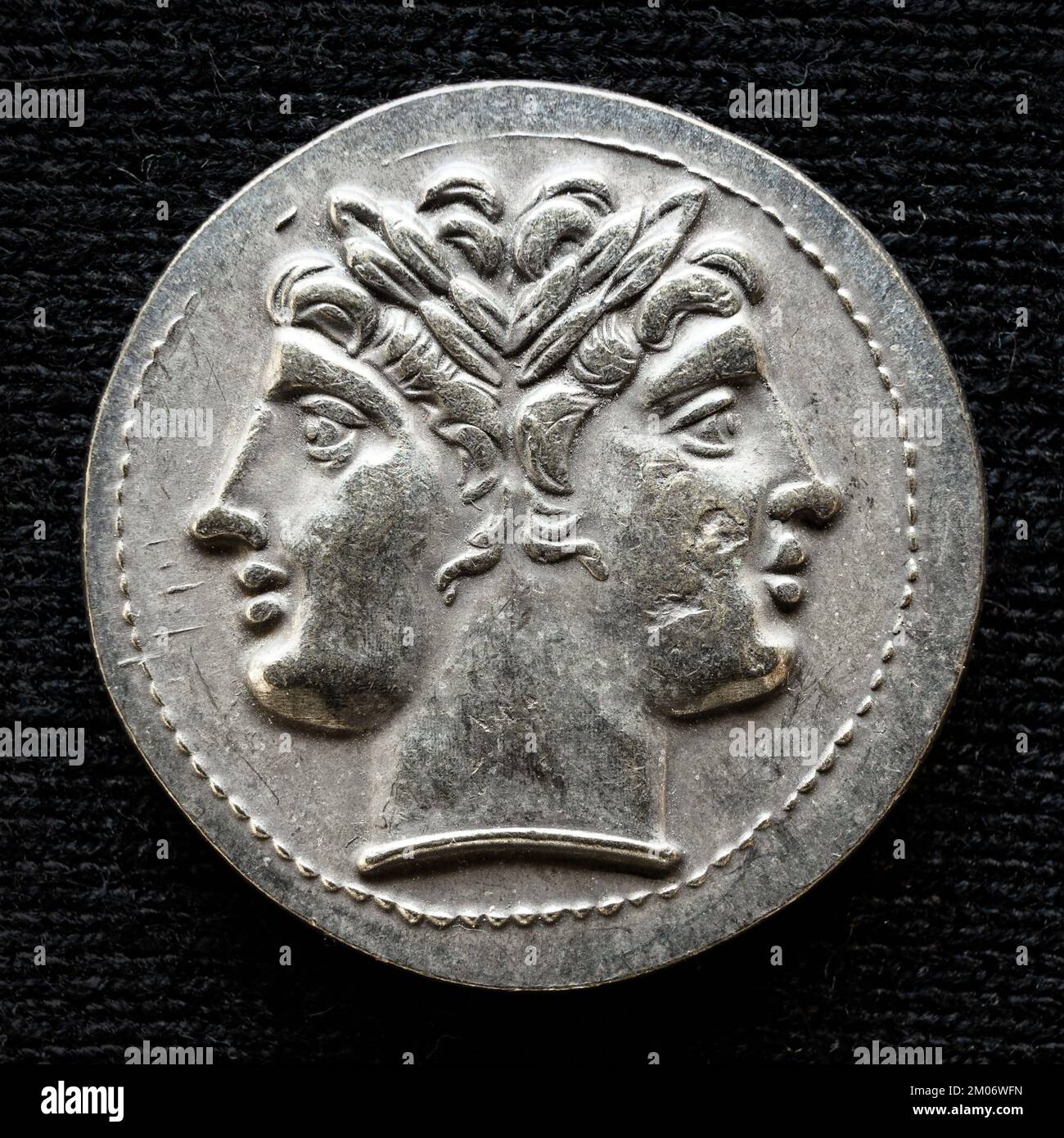 Ancient coin showing two-headed Roman god Janus, 225-214 BC. Old rare money, silver didrachm isolated on dark background, macro. Concept of Rome, valu Stock Photo
