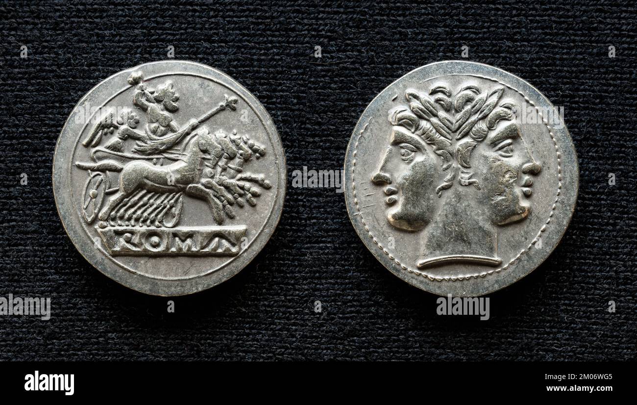 Ancient Roman coin showing Jupiter on horses and god Janus, 225-214 BC. Old rare money, silver didrachm isolated on dark background, macro. Concept of Stock Photo