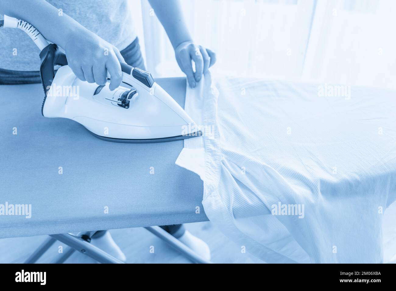 Female hands ironing white shirt collar on ironing board Stock Photo
