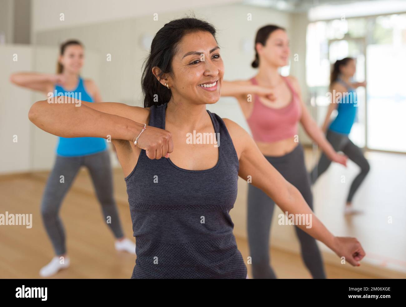 Cheerful hispanic woman practicing vigorous dance in group class Stock Photo