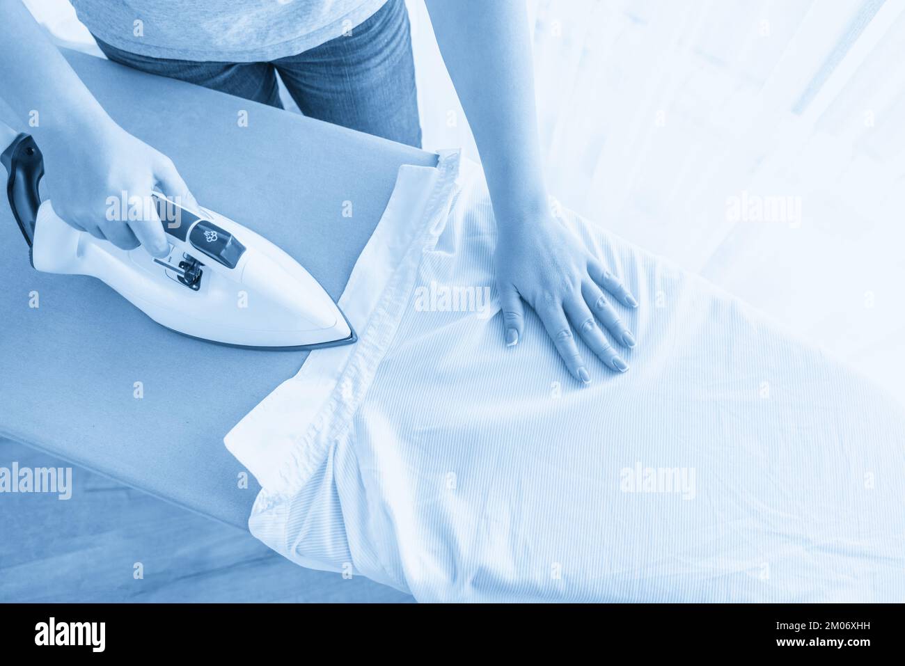 Female hands ironing white shirt collar on ironing board, view from