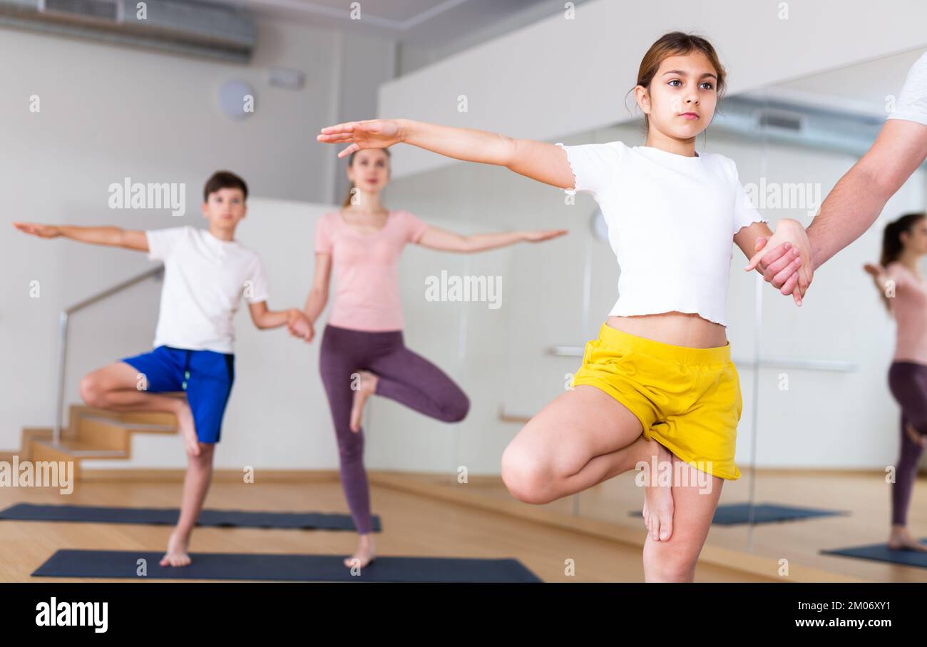Girl exercising tree pose during family yoga training Stock Photo - Alamy
