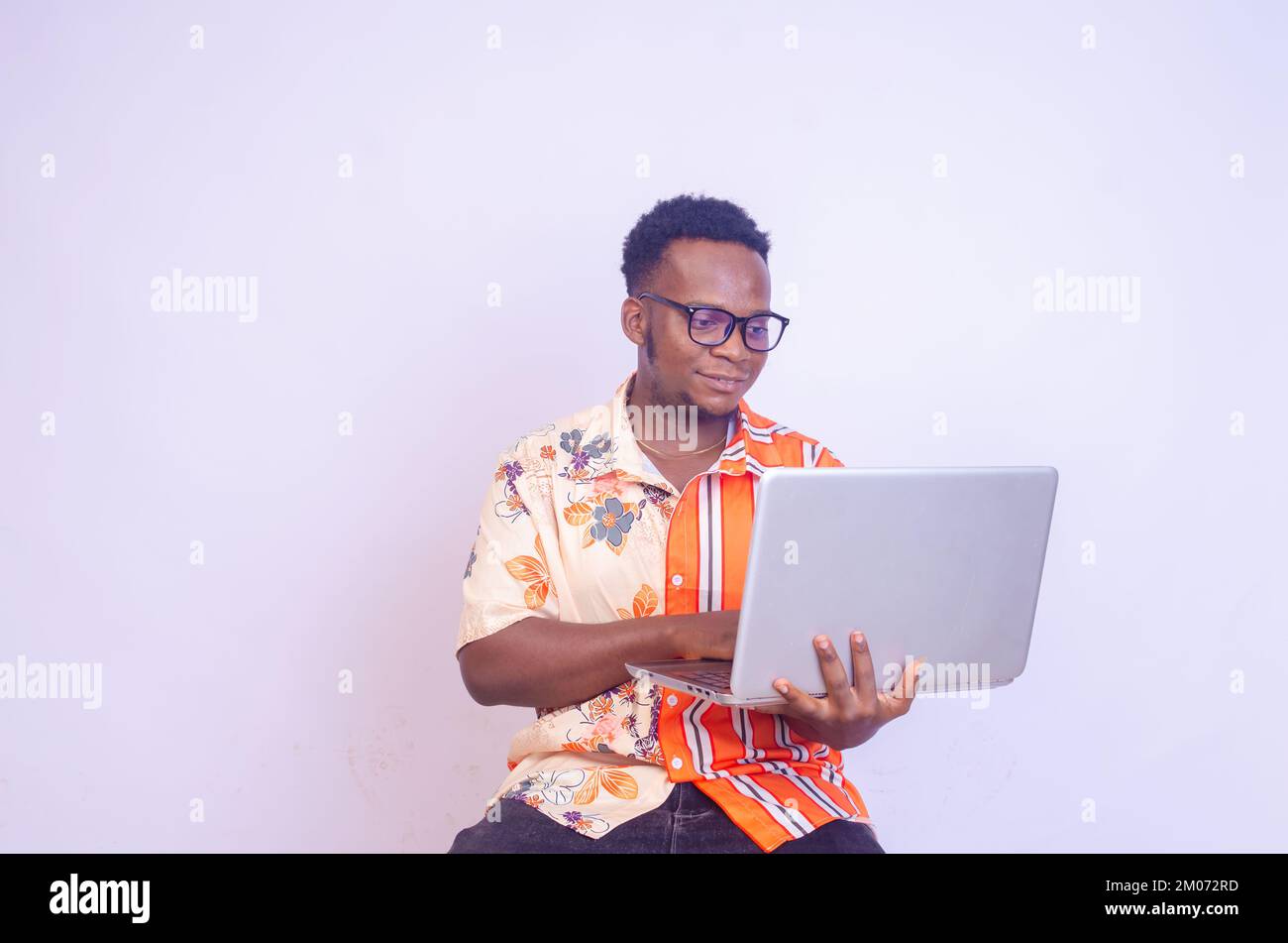 Young smiling african american man sitting and using laptop computer ...
