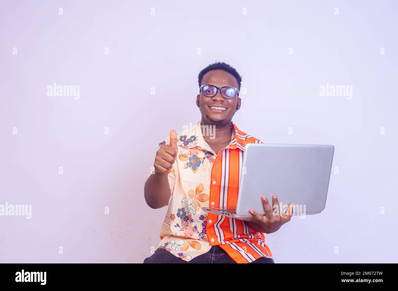 Young smiling african american man sitting and using laptop computer ...