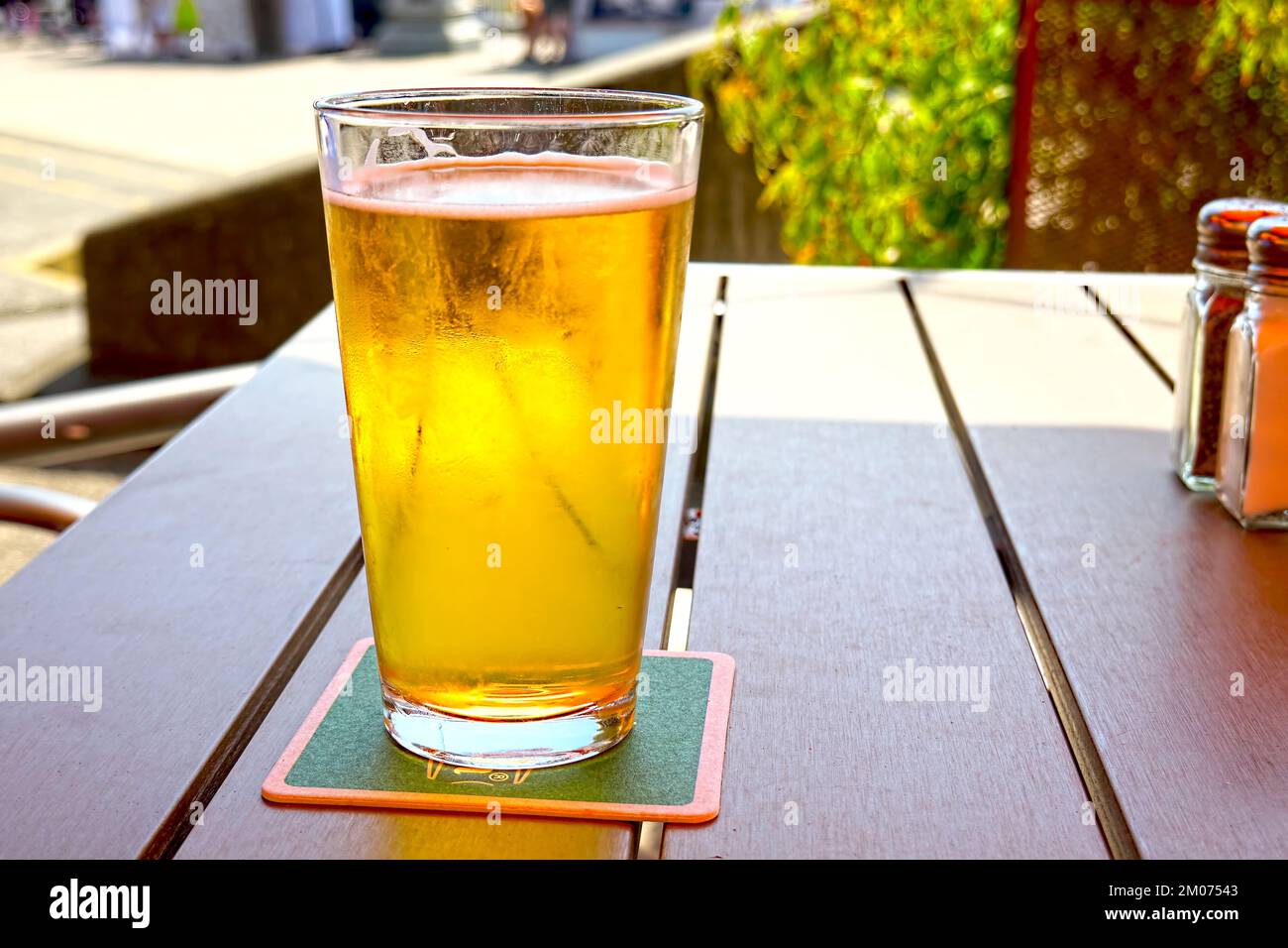 Glass of Pale Ale on an outdoor patio table. Stock Photo
