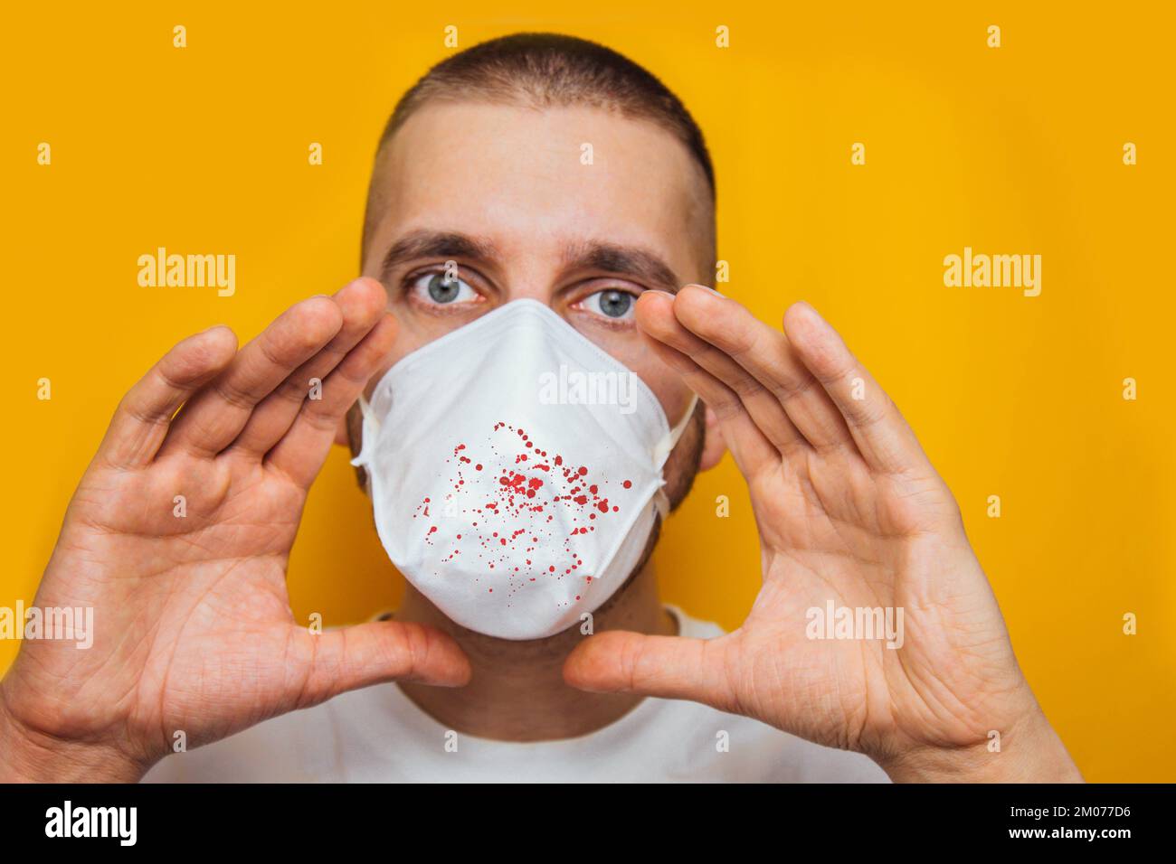 Young guy in a respirator on a yellow background. Coughs up blood