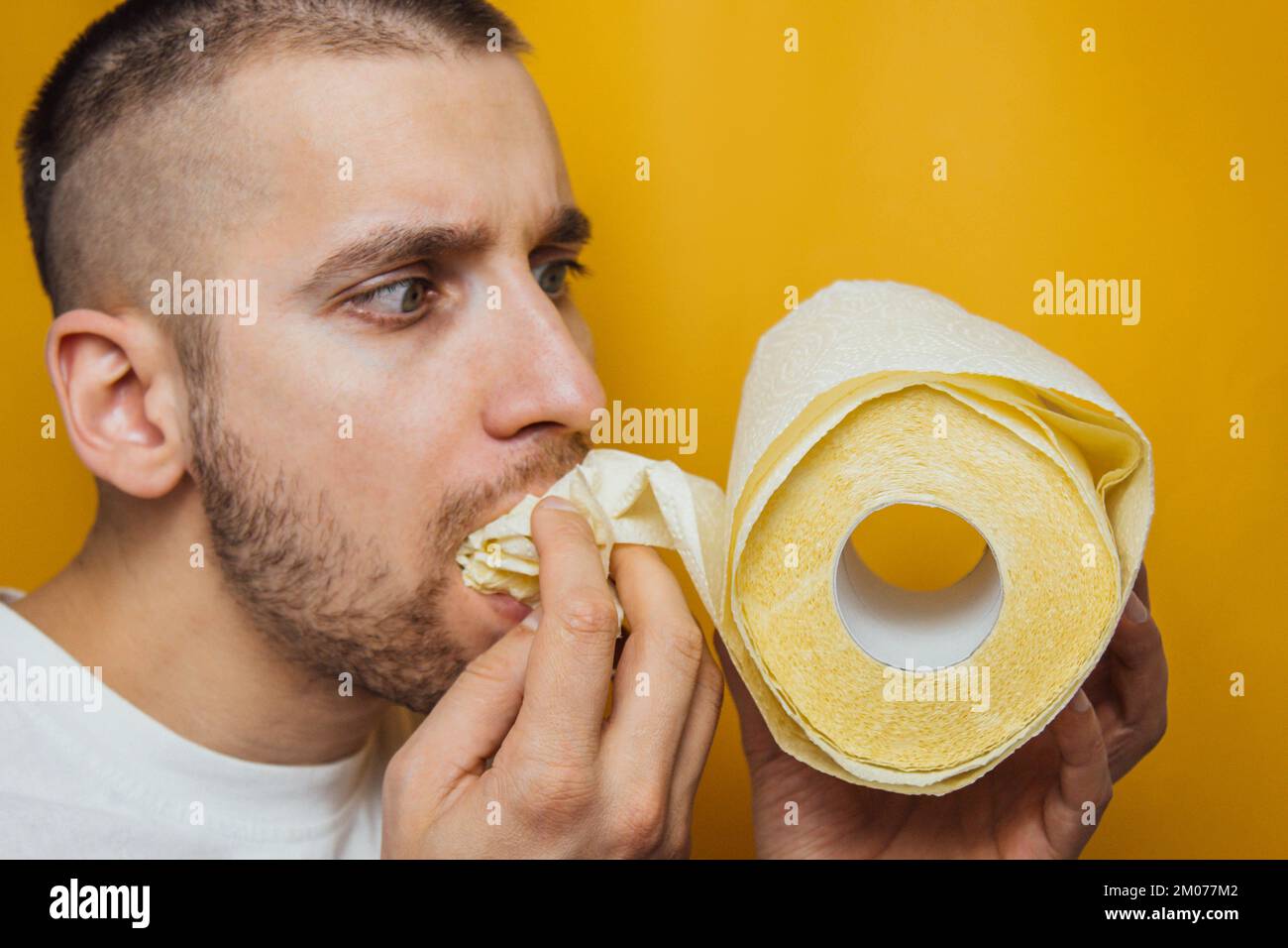 Funny caucasian young man eats a toilet paper. He to buy food in