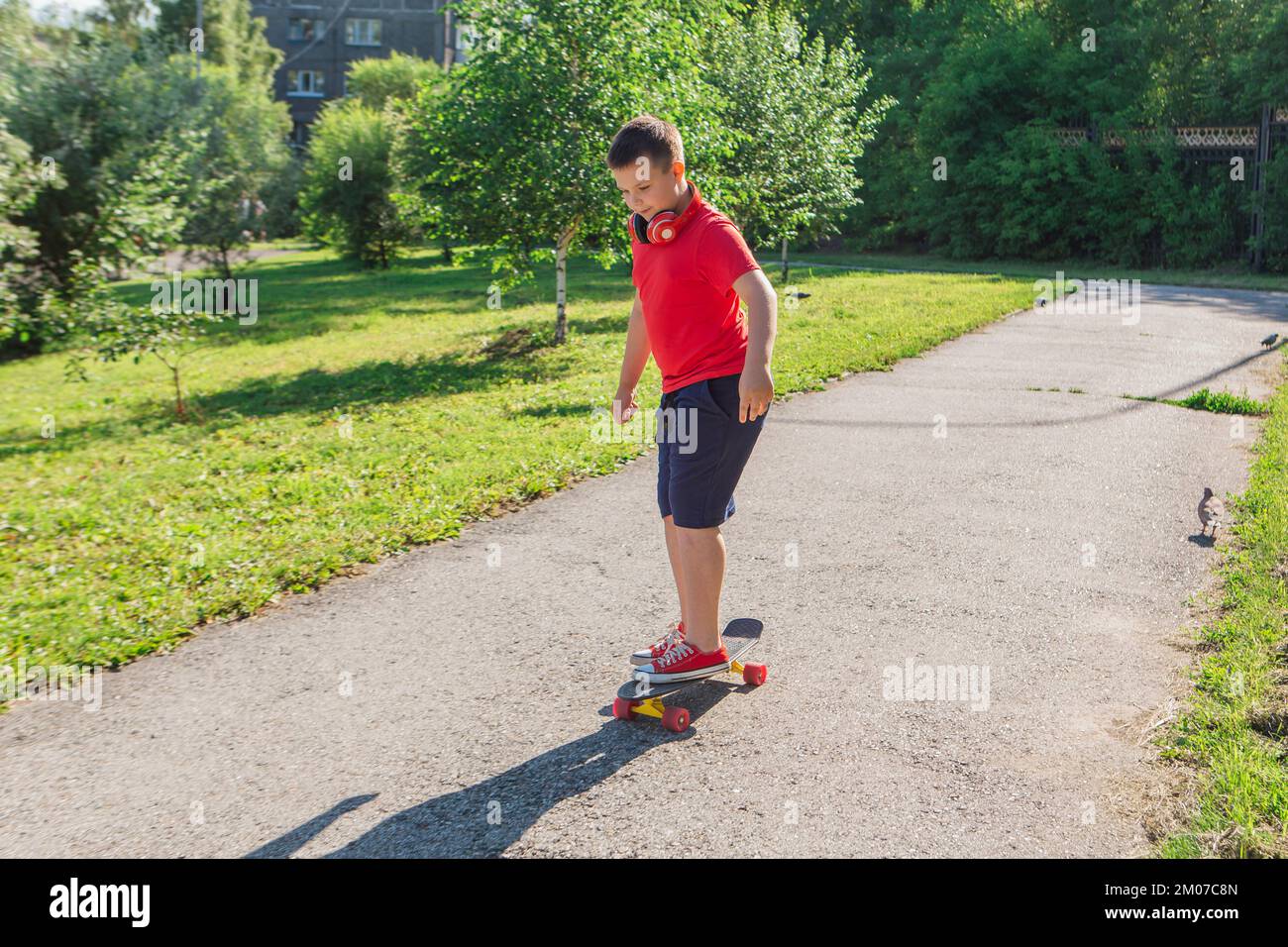 Chubby ten years old boy spends free time training skating in the city park. Cute nice boy