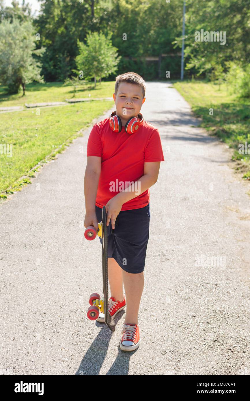 Chubby ten years old boy spends free time training skating in the city park. Cute nice boy