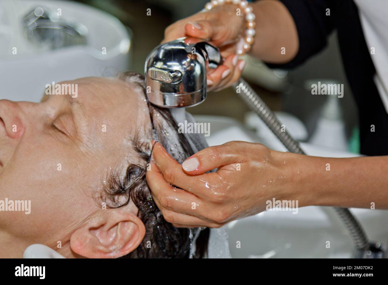 cheerful elderly woman enjoys a head massage while washing her hair by a professional