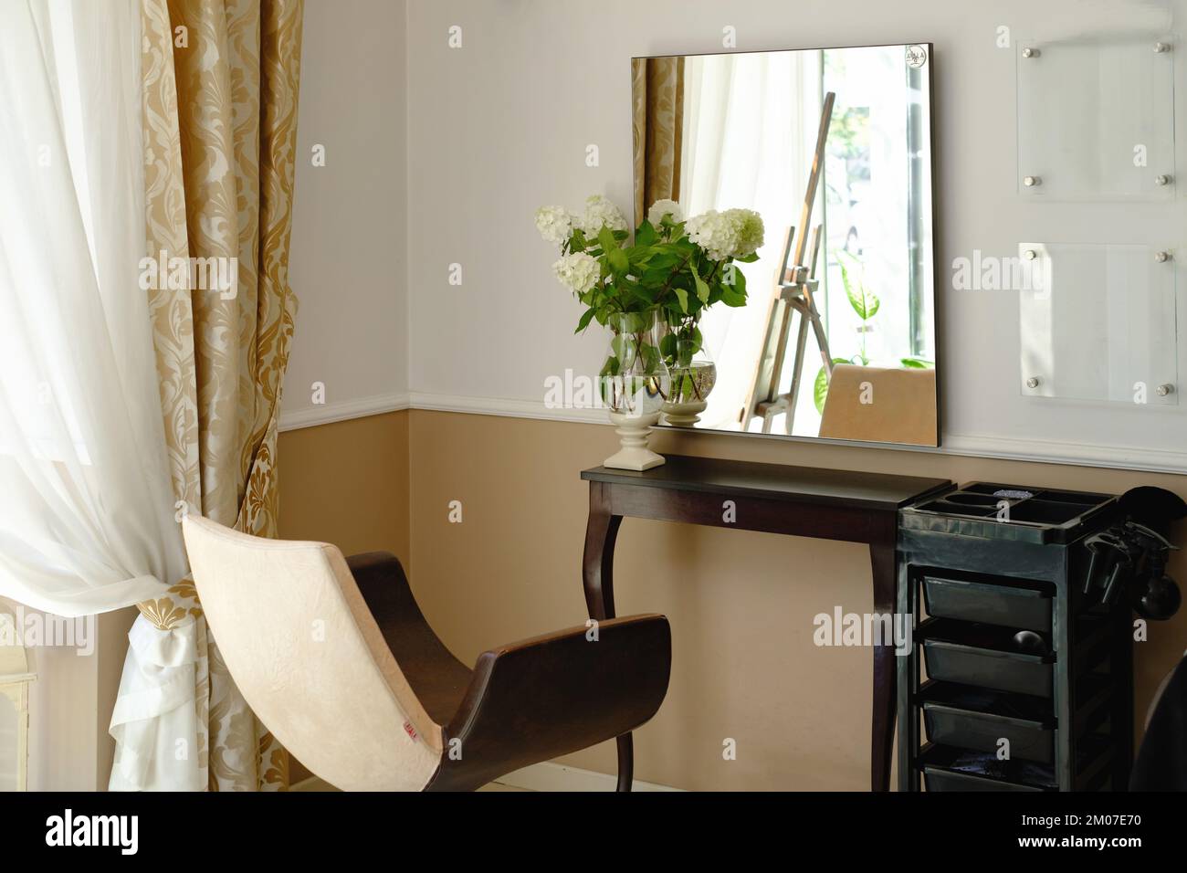 Beauty salon interior with flowers. Hairdressing procedures in luxe beauty salon, free space. Mirror in front of seat Stock Photo