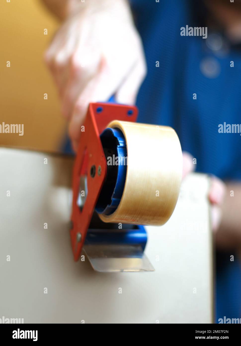 Ready for delivery. A man using a tape dispenser to seal a cardboard
