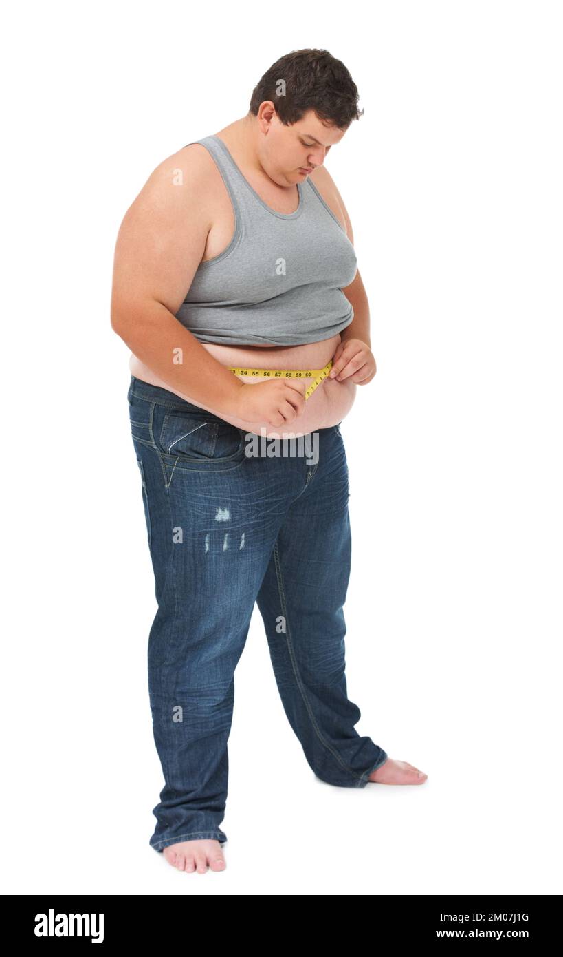 Watching his weight. An obese young man measuring his waist with a measuring tape against a white background. Stock Photo