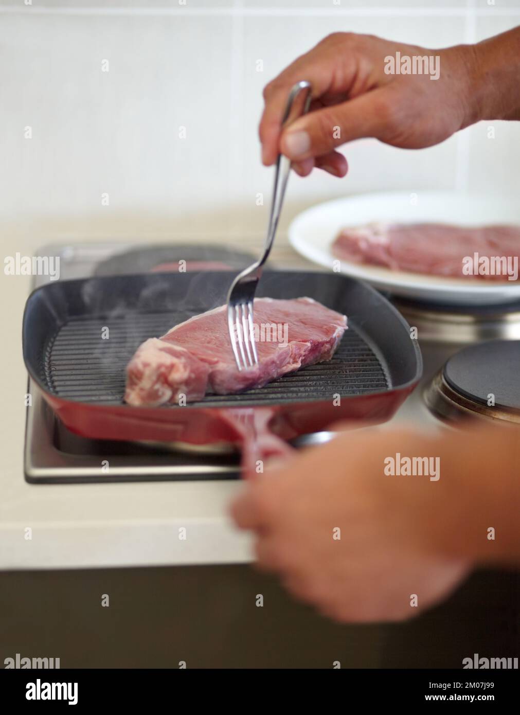 Healthy, oil-free cooking. Cropped image of a man cooking a steak on a stove. Stock Photo