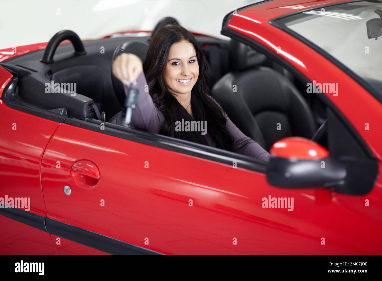 Care to join me for a drive. Young woman sitting in her new car and