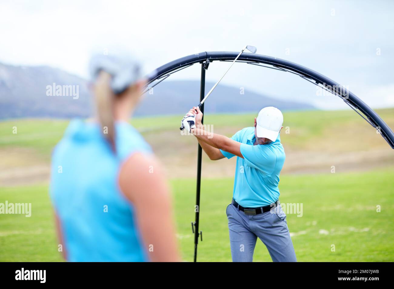 Ensuring she learns the perfect swing. Cropped image of a male coach instructing his female student using a ring to adjust and correct her swing. Stock Photo