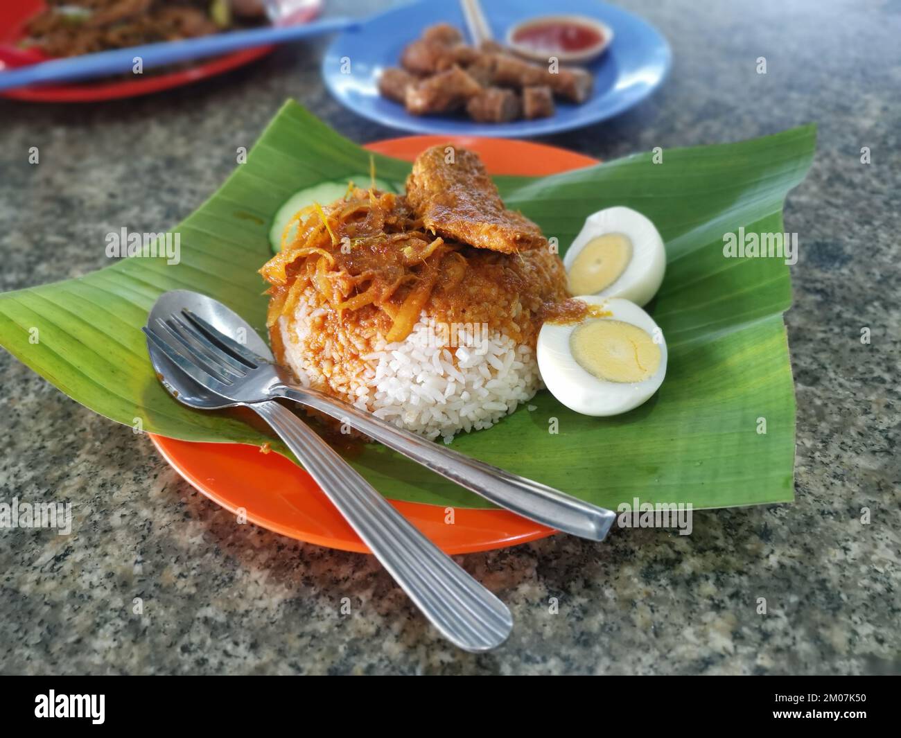 a plate of savoury spice gravy rice with fried anchovies on banana leaf Stock Photo