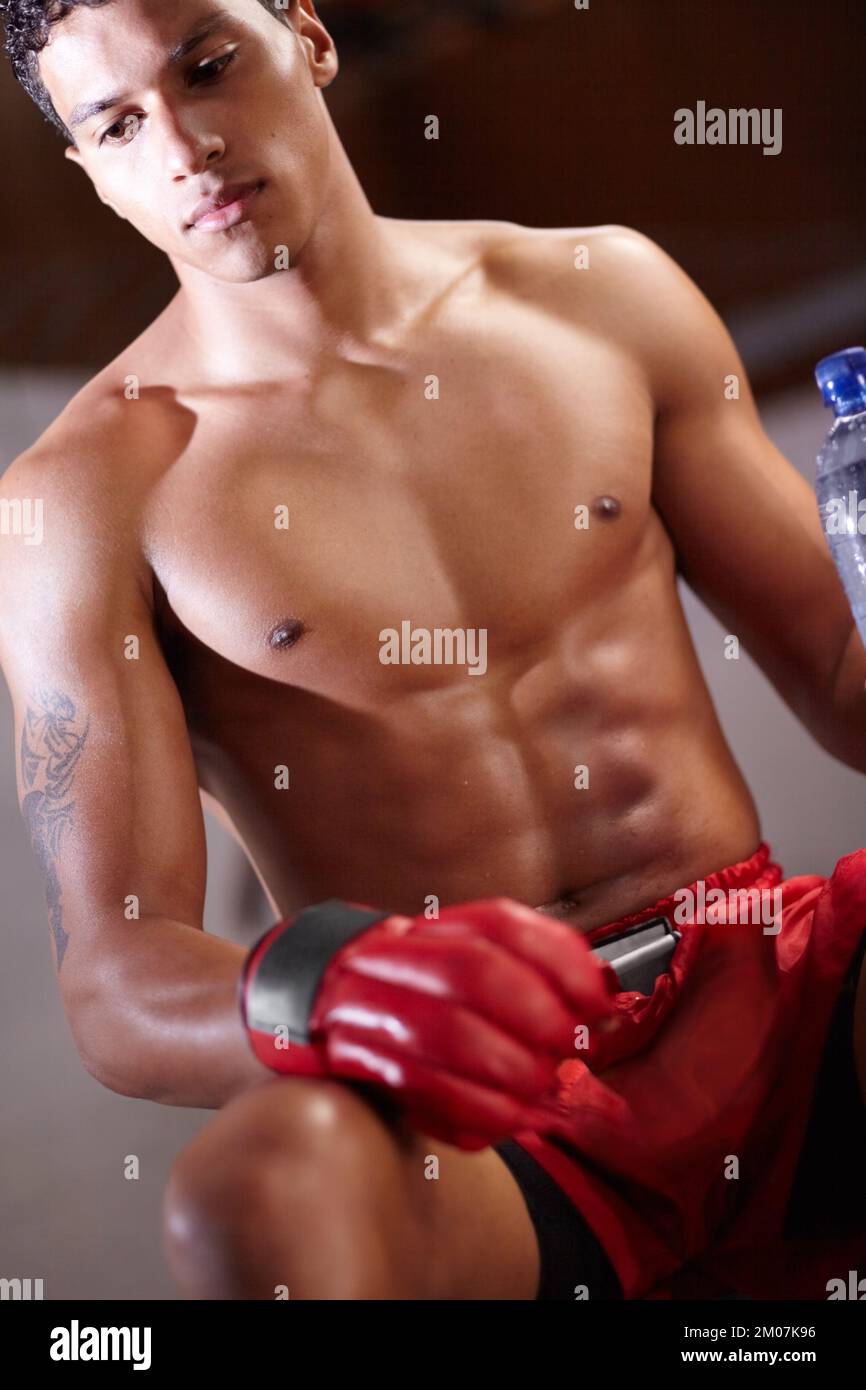 Feeling focused for this match. A young boxer sitting down and holding a bottle of water. Stock Photo