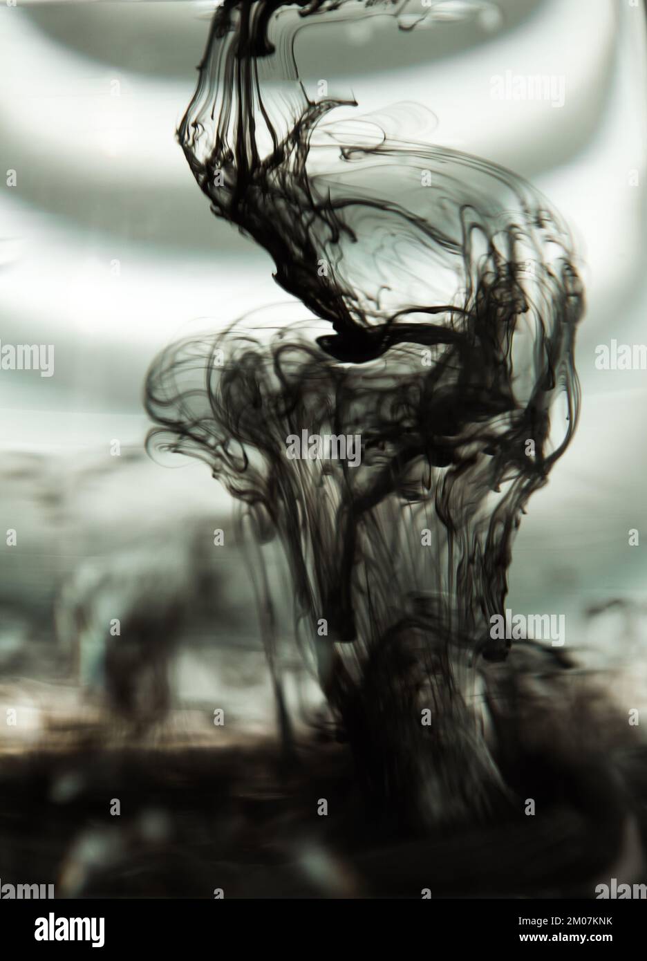 a cloud of ink in a transparent glass cup with clear water against the ...