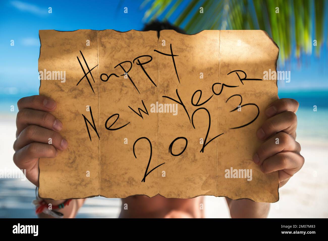 2023 Happy new year travel and lifestyle concept with map and tourist man on tropical island beach. Banner for winter, summer exotic family vacation. Stock Photo