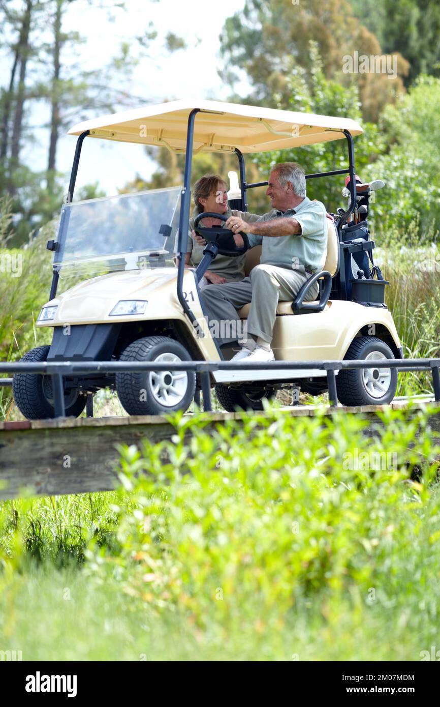 Retired and enjoying lifes small pleasures. A mature couple discussing their last hole while driving a golf cart. Stock Photo