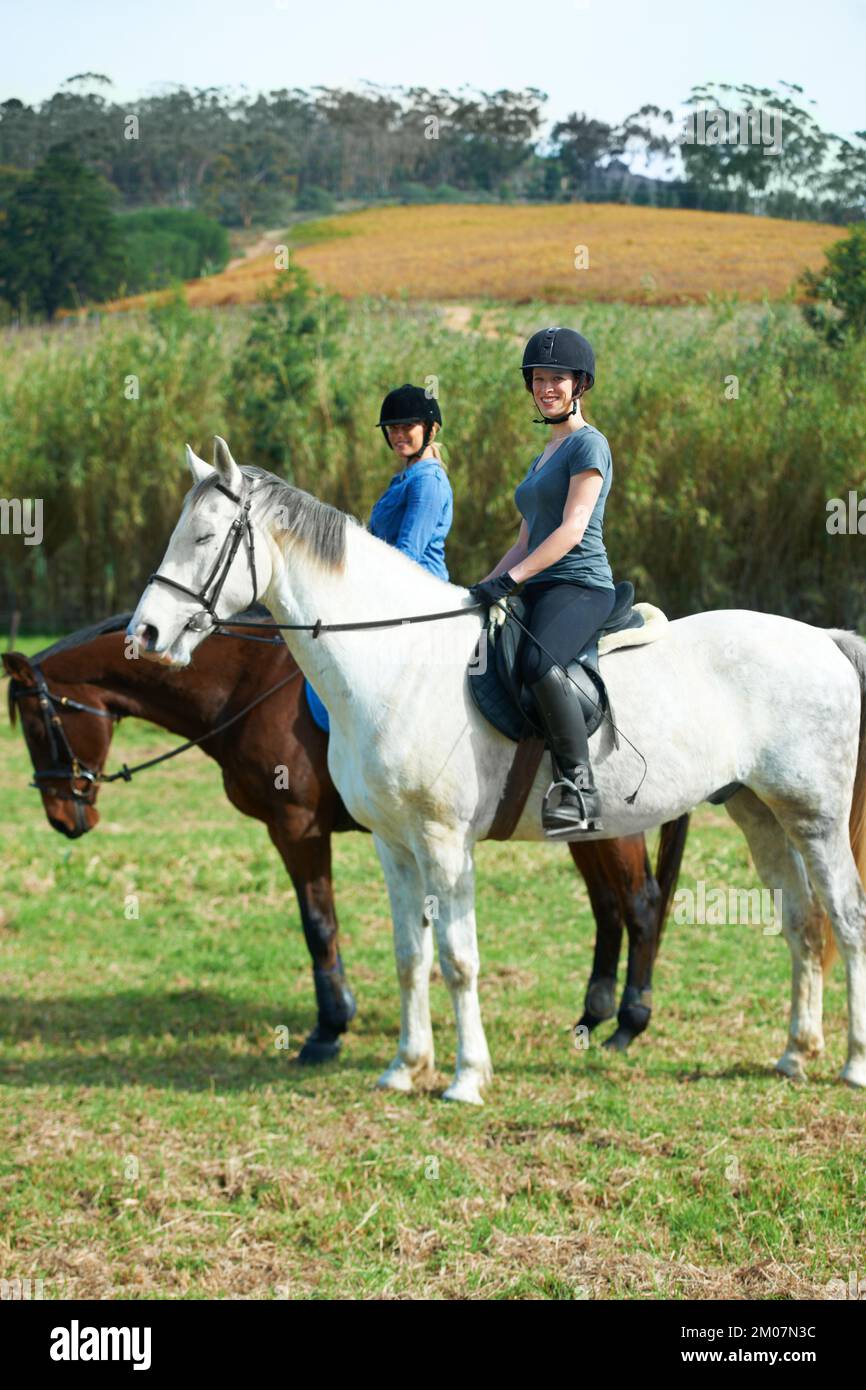 Theyre ready for some serious horse riding. Portrait of two young women on horseback outside. Stock Photo