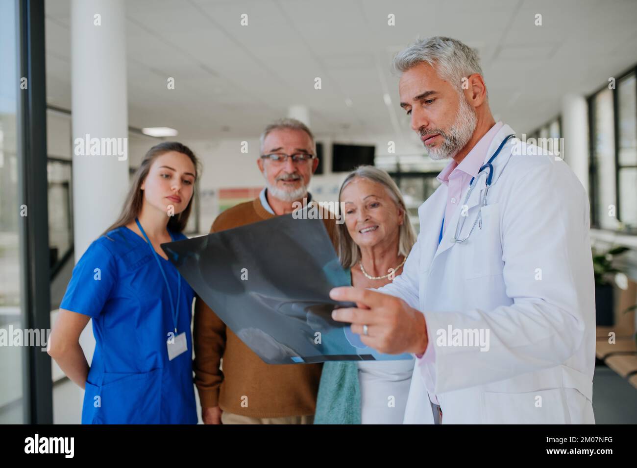 Doctor showing x-ray image to patients, explaining diagnosis. Stock Photo