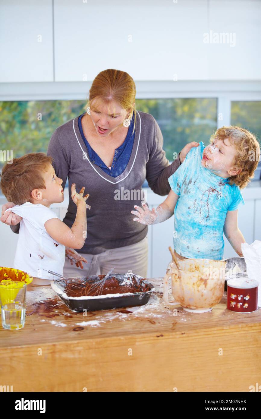 Caught in the act. Two boys being scolded by their mother for messing up her kitchen. Stock Photo